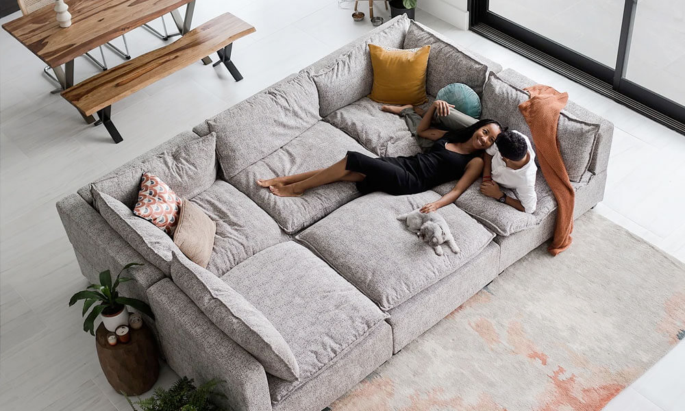 6-piece grey upholstered Pit Sectional Sofa in a living room with a couple sitting in it