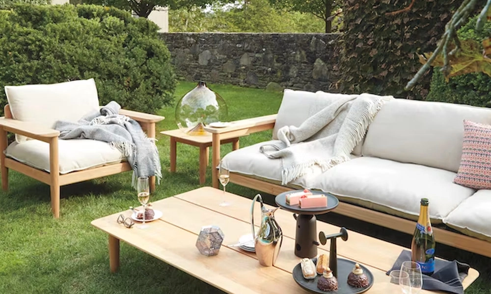 Wooden frames sofa set with white cushions and light grey blankets, a wooden coffee table in a garde