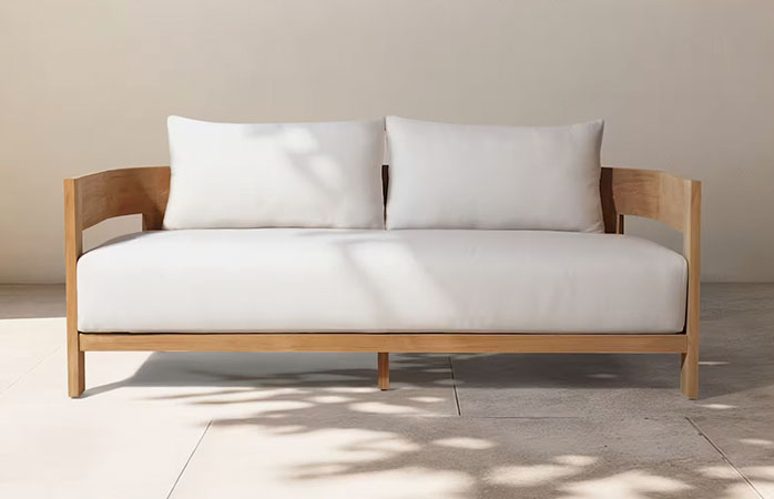 Curved teak outdoor sofa with white cushions
