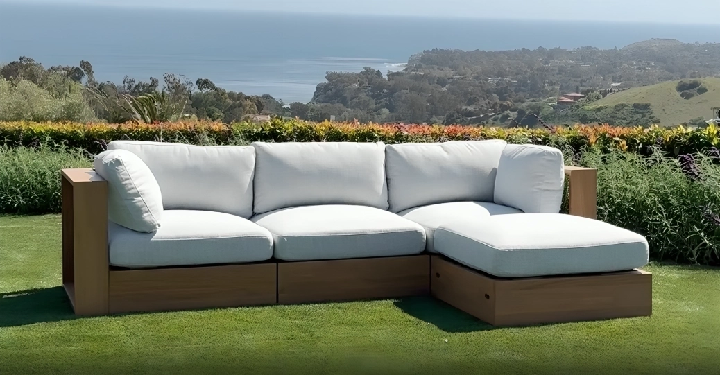 modern white L shaped sectional with wooden frame in a garden and near the ocean.
