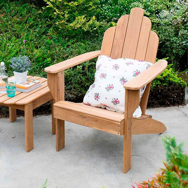 All-Natural Teak Adirondack Chair with a flowered cushion and a teak coffee table in a garden