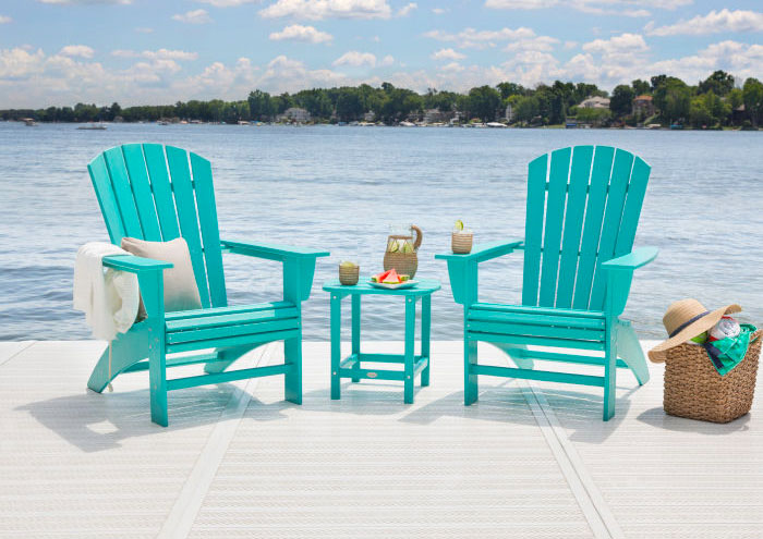 Two Aruba blue Curveback Adirondack Chairs with a ottoman in a lakeside porch