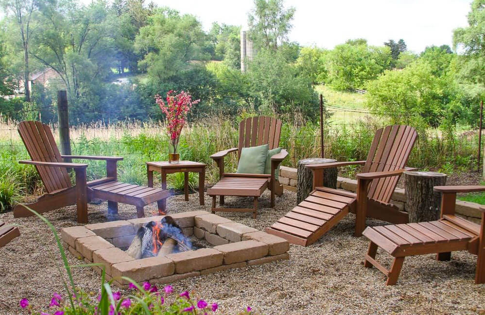 Four Eucalyptus Adirondack Chairs and a ottoman near a fire pit in a garden