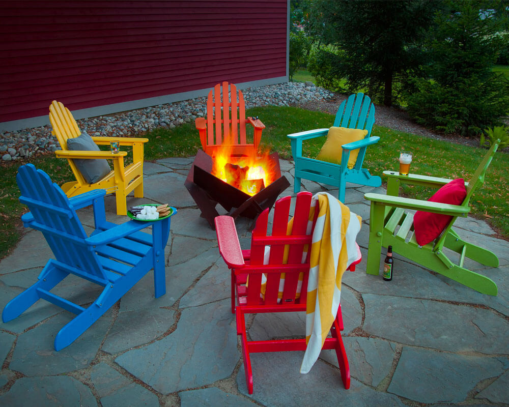 Six colored adirondack chairs with a firepit in the center in a patio