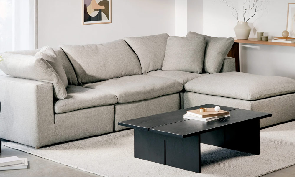 Grey upholstered sofa with grey throw pillows in a modern living room with a black coffee table