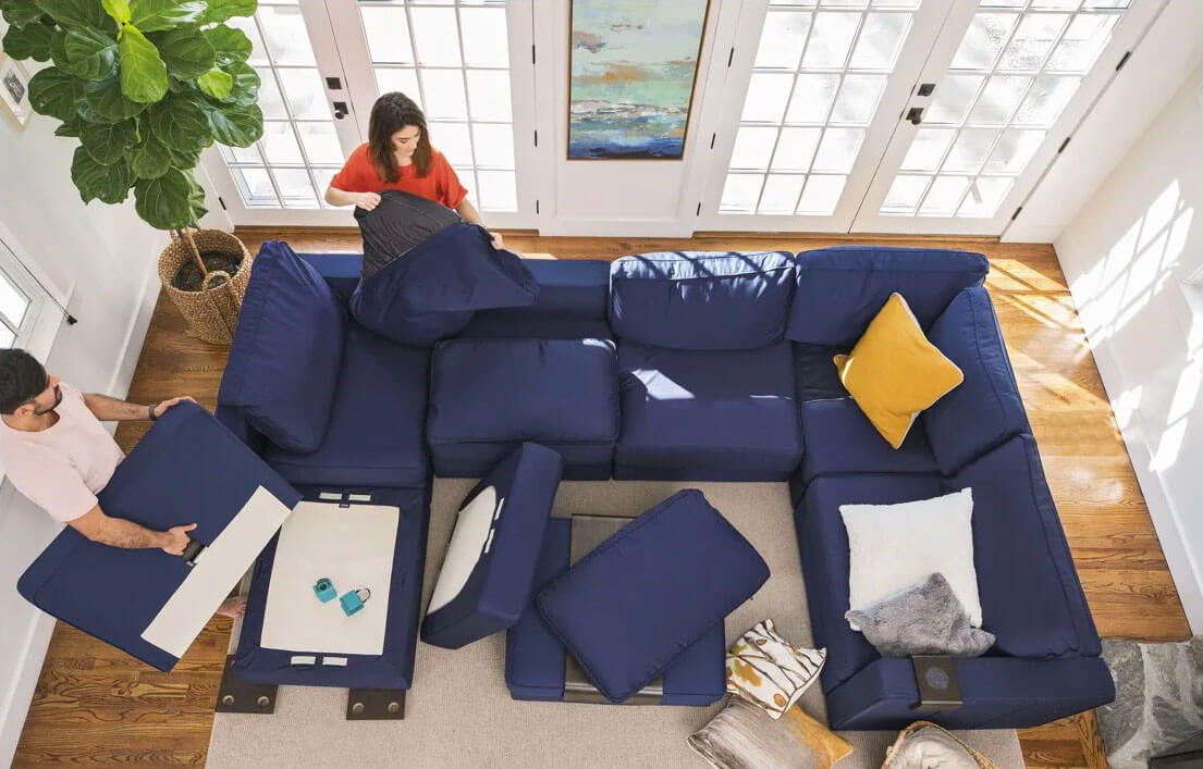 A couple assembling a blue sectional sofa in a bright living room