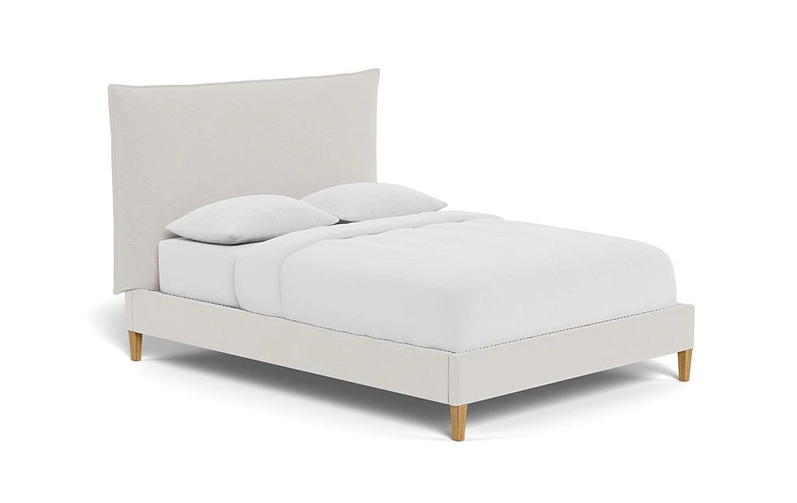 light grey upholstered bed with a matching tall headboard, a attress with bedding sheets and pillows