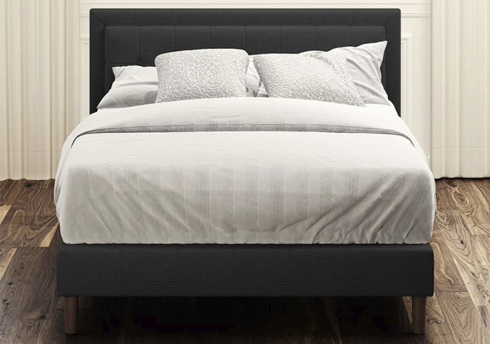 Grey upholstered platform bed with square stitched headboard and wooden legs
