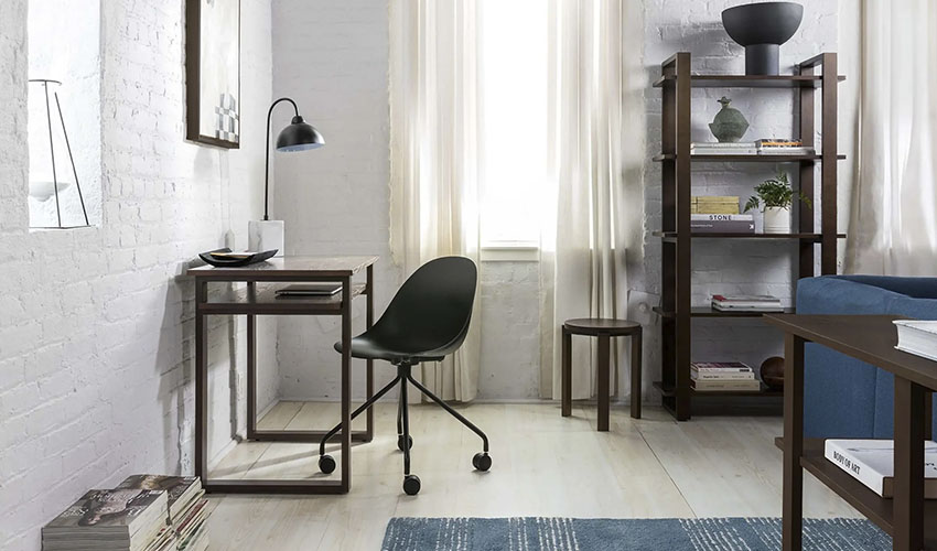 Minimalistic wooden desk with a laptop, a pot with a chair near a window