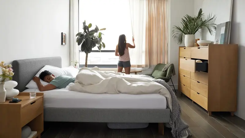 Man sleeping in a bed with a grey upholstered bedframe in a modern bedroom