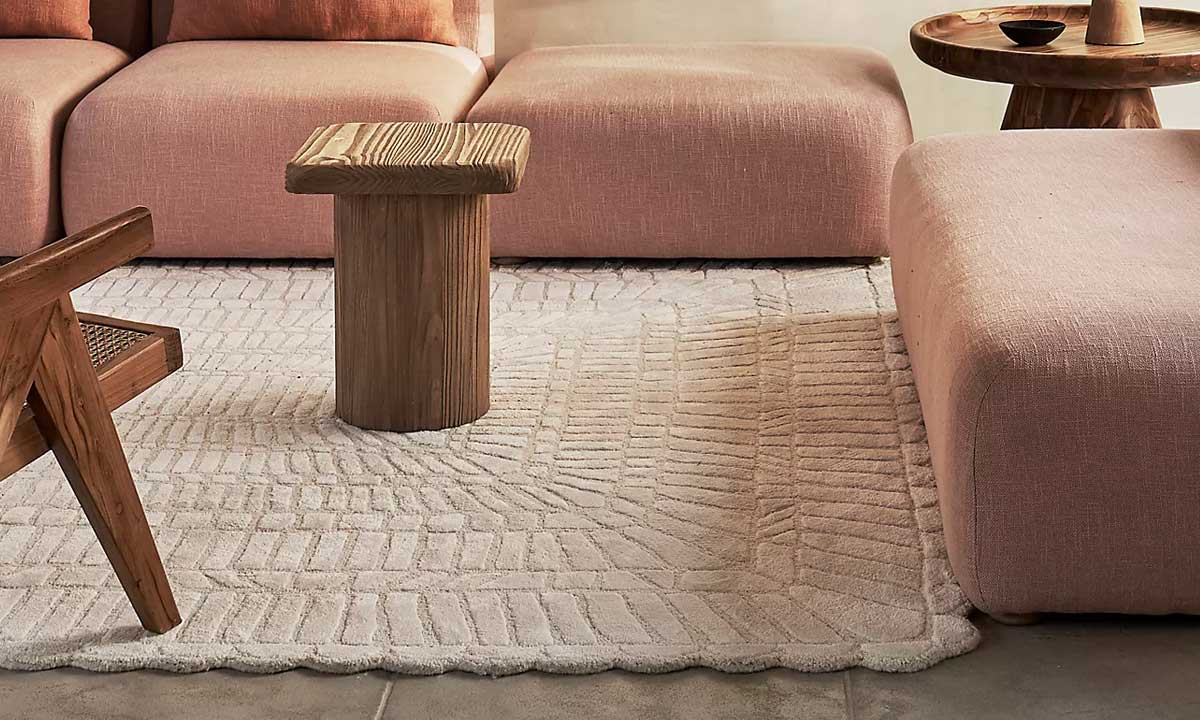 Light beige textured Rug in a living room with a pink sectional set and an accent chair