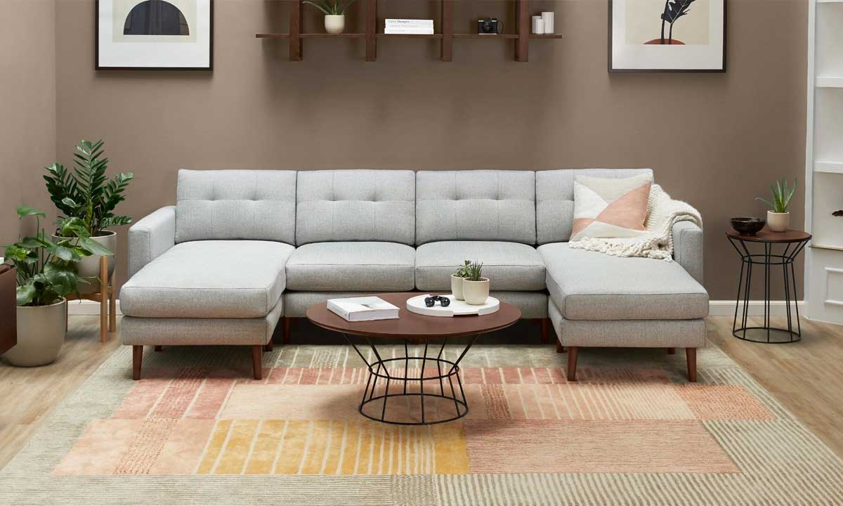 Modern patterned Rug in a living room with a u-shaped gray sofa and pots with plants