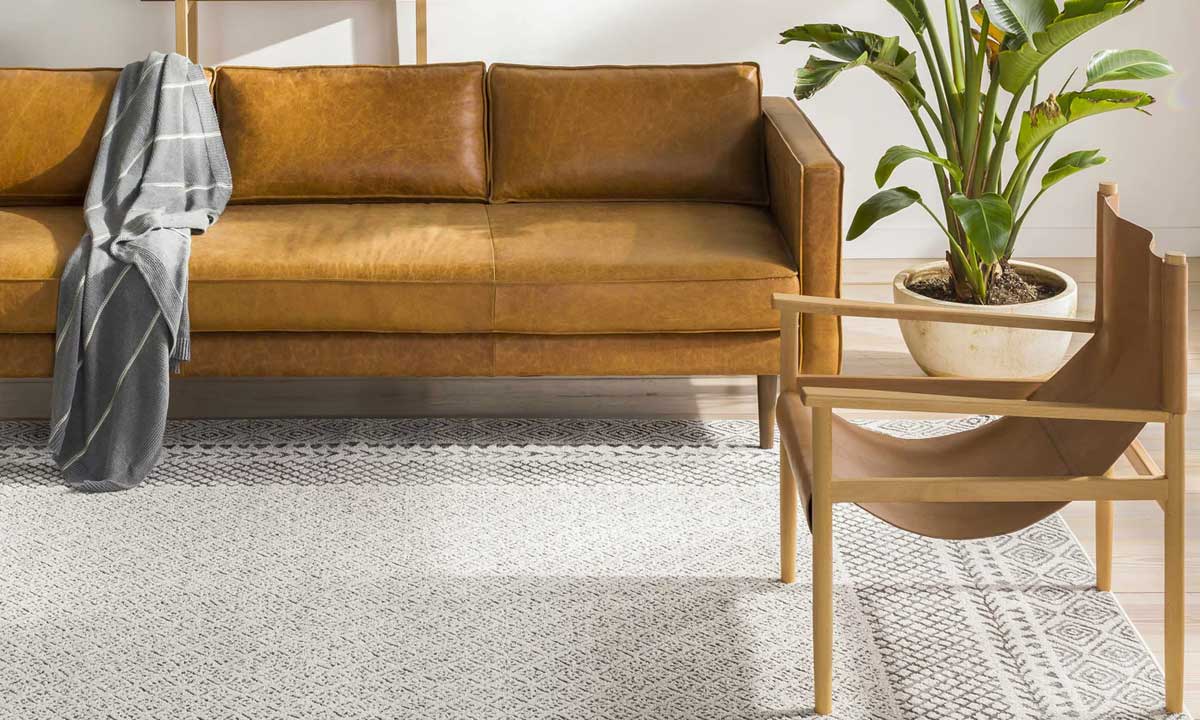 Burdette Soft Neutral Rug in a living room with a mustard yellow sofa with a gray sofa blanket