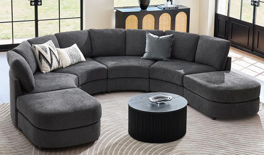 Grey upholstered curved Sofa with accent pillows