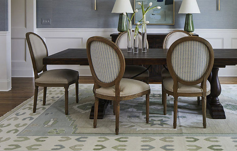 Light gray rugh with blue geometric designs in a living room with a brown dining table and chairs