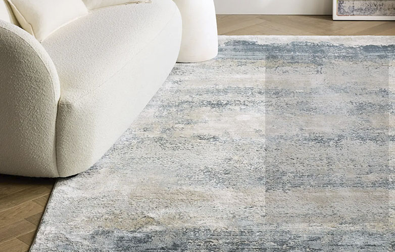 Blue, gray white and light blue Rug in a living room with a ivory sofa