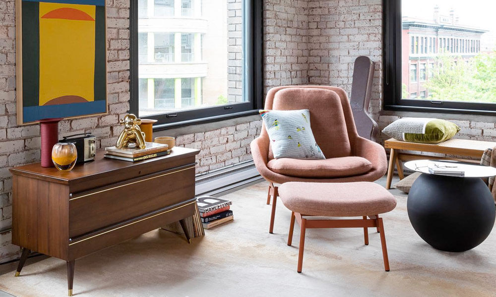 Living room with a wooden credenza and a light coral accent chair with an ottoman