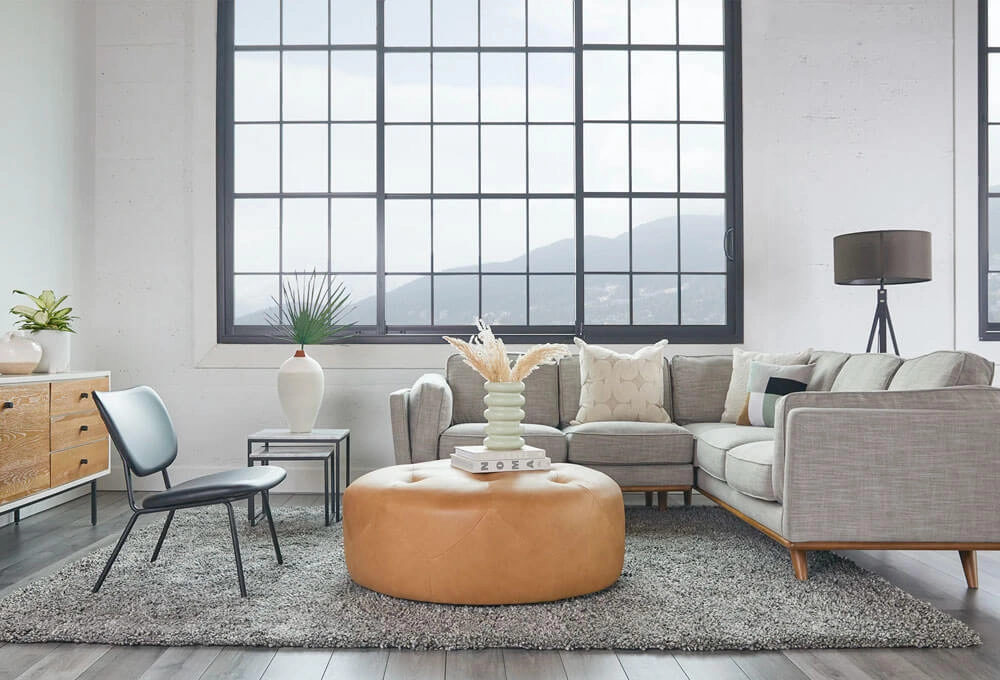 Leather Ottoman in a living rooom with a modern L-shaped light grey sofa and a black accent chair