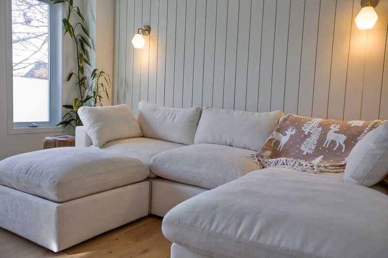 White L-sectional couch in a living room with natural light and neutral color palette.