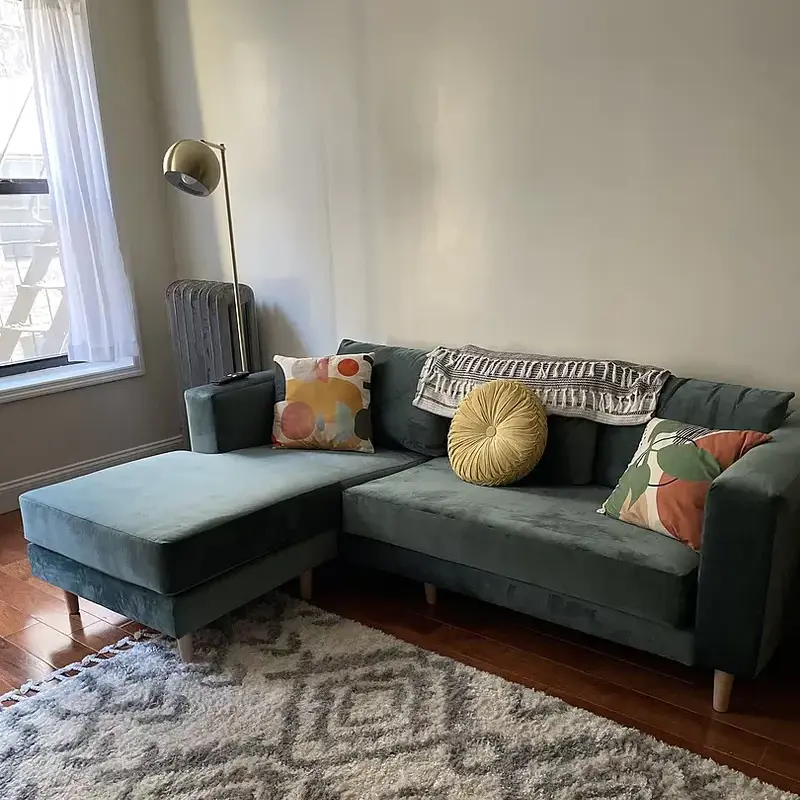 Light gray L-sectional sofa with wooden legs.