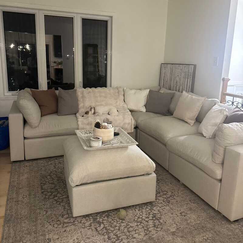 White L-sectional couch in a living room with natural light and neutral color palette.