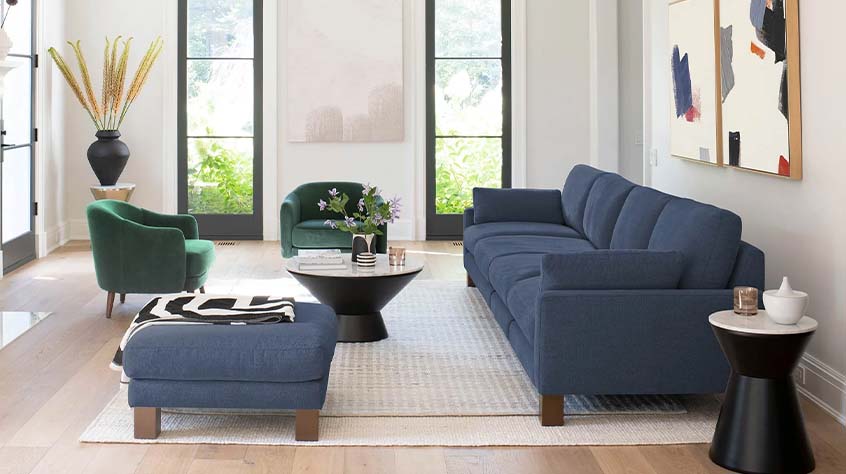 blue upholstered deep sofa with light wooden natural legs in a living room with a beige rug