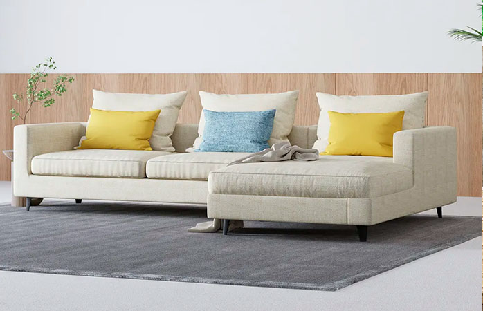 Beige sectional sofa with a brown blanket in it in a modern living space with a grey rug