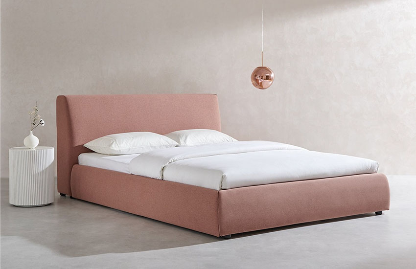 Coral Haze upholstered bed with a headboard, a mattress with white sheets and two pillows