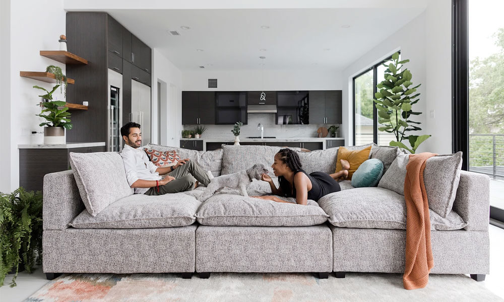 Grey upholstered pit sectional sofa with a couple sitting in it having a good time
