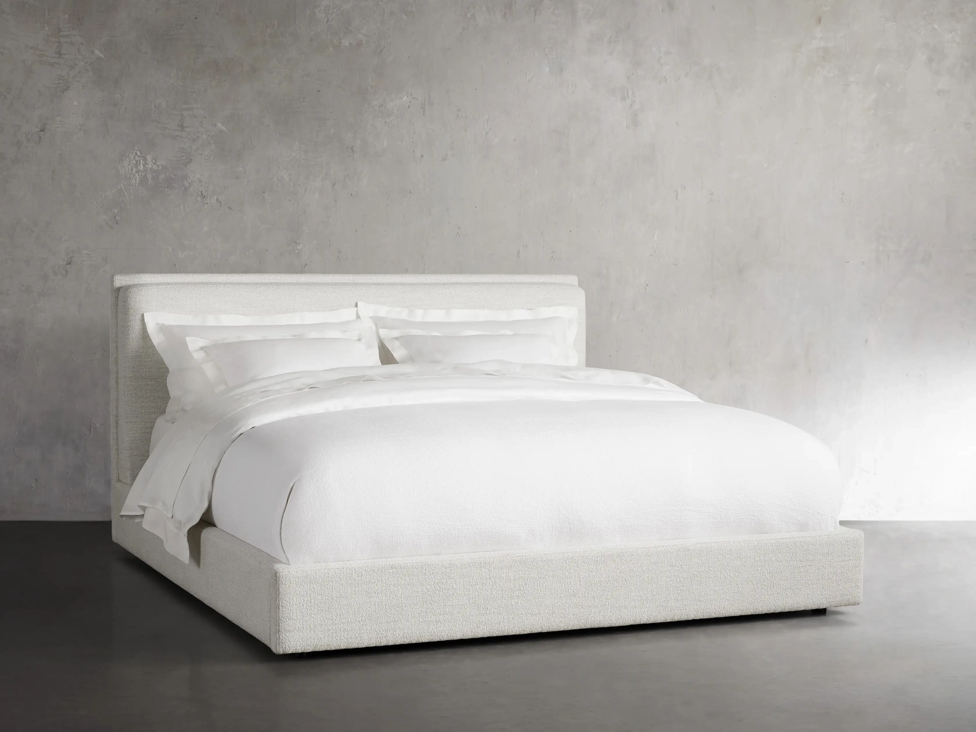 White solid platform bed with a mattress and pillows with white bedwear