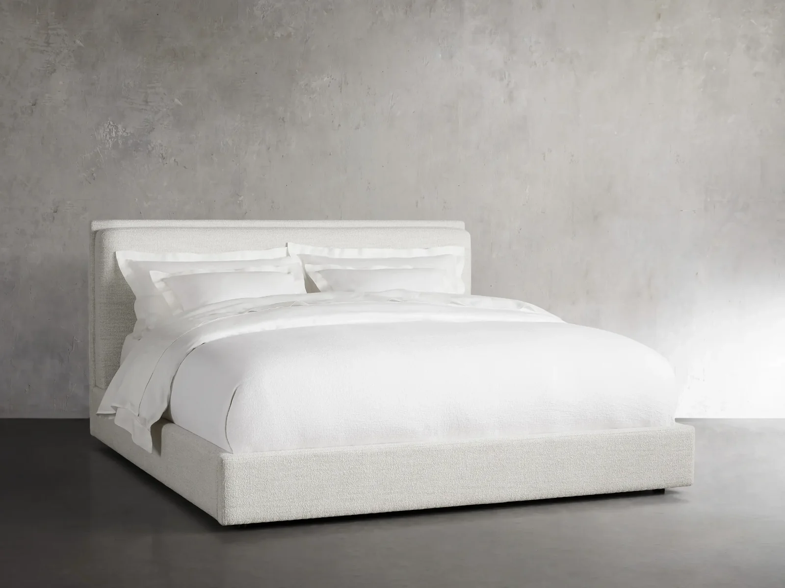 White solid platform bed with a mattress and pillows with white bedwear