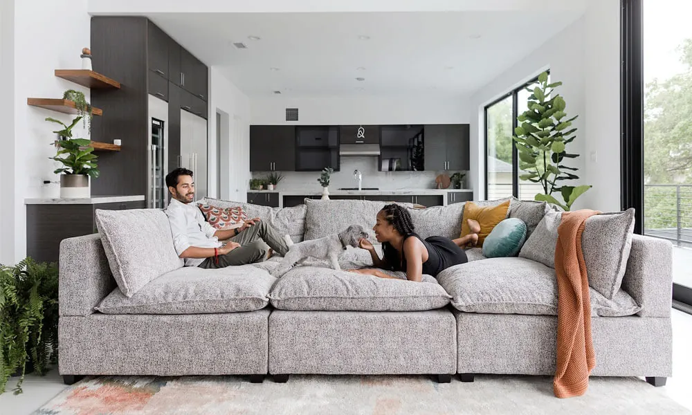 Grey upholstered pit sectional sofa with a couple sitting in it having a good time