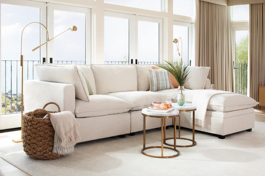White upholstered sofa in a bright living room with white rug and two small round coffee tables