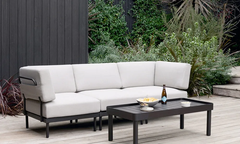 Black framed outdoor sofa with light grey cushions in a patio