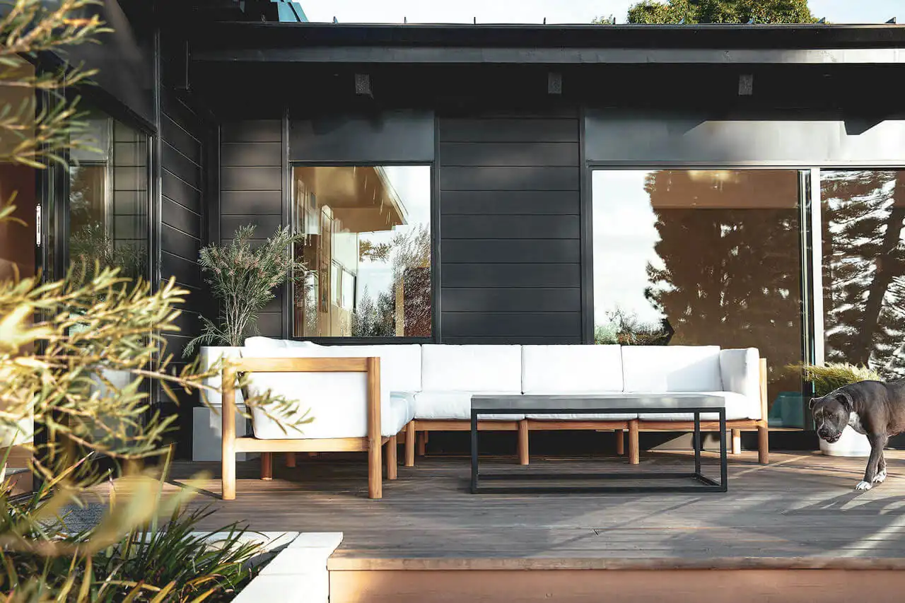 Wooden frame white sectional sofa in an utdoor space with a black aluminum coffee table