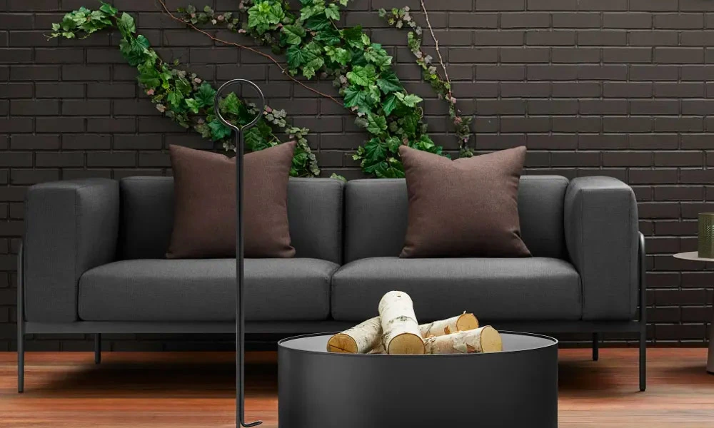 Black coffee table with fire pit, next to black sofa with brown cushions