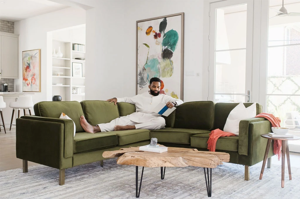 Green velvet sectional sofa with a man sititing in it