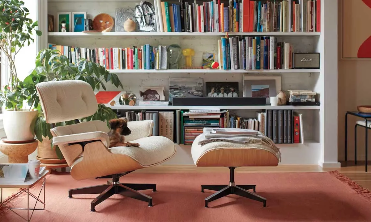 A cozy living room with a chair and ottoman positioned in front of a well.stocked bookshelf