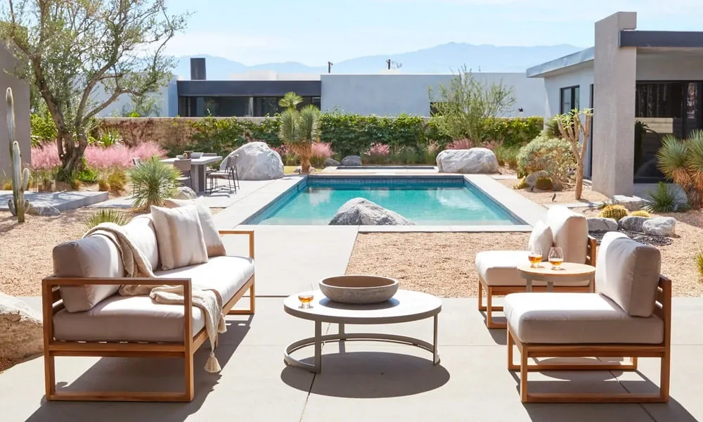 Outdoor wooden furniture set in a patio next to a pool in a sunny day