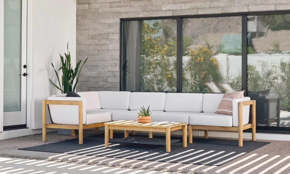Wooden outdoor sofa with white cushions on a patio in a sunny day