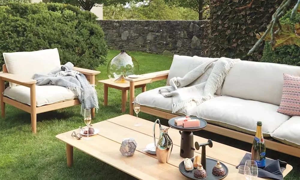 Wooden frames sofa set with white cushions and light grey blankets, a wooden coffee table in a garde