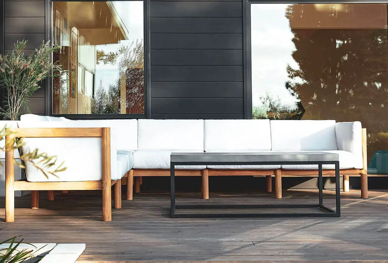 Wooden outdoor sofa with white cushions on a patio in a sunny day