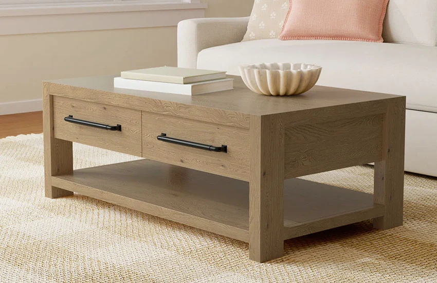 Natural wooden coffee table with two drawers and a shelf with books and decor in a living room