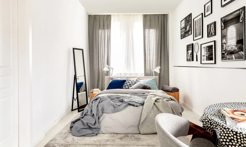 A serene bedroom with a plush bed, a modern dresser and a TV on the wall