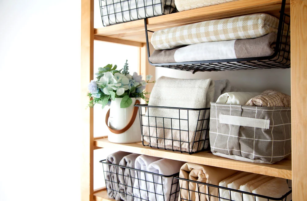z wooden shelf displaying neatly arranged baskets and folded towels
