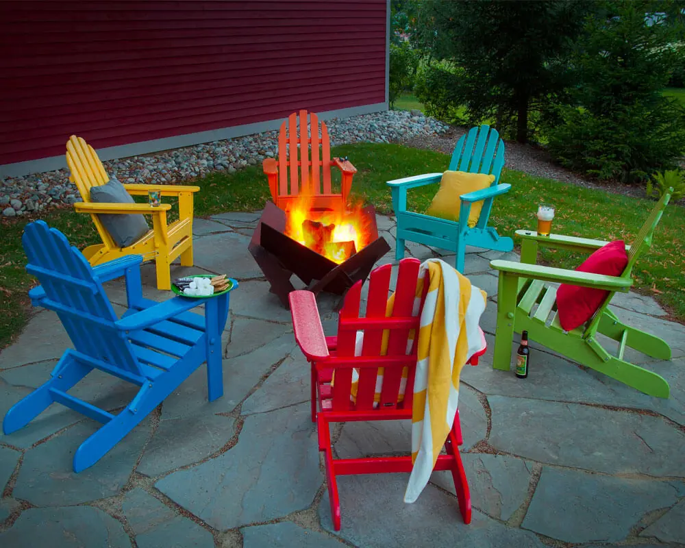 Six colored adirondack chairs with a firepit in the center in a patio