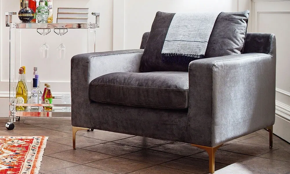 Grey accent chair with metal legs in a cozy nook near a small bar