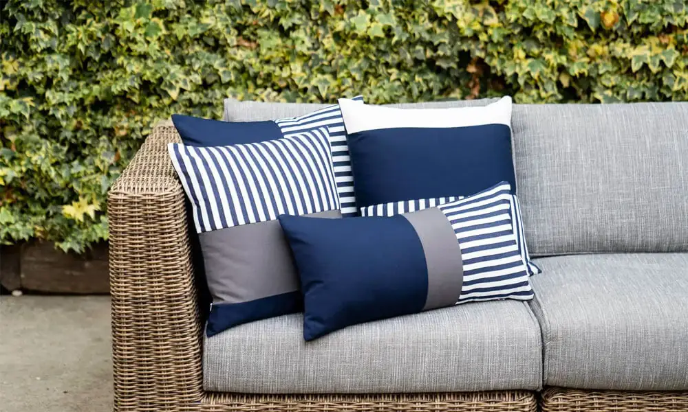 Outdoor Throw Pillows in the top of outdoor sofa with grey back and seat cushions and wicker frame