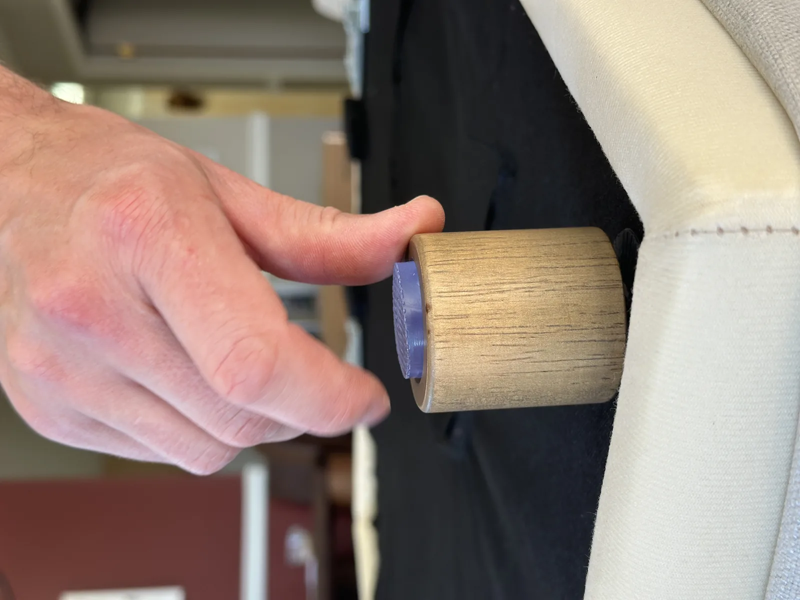 A short light oak leg with a grey rubber anti-slip pad on its base, held against the underside of the sofa during assembly