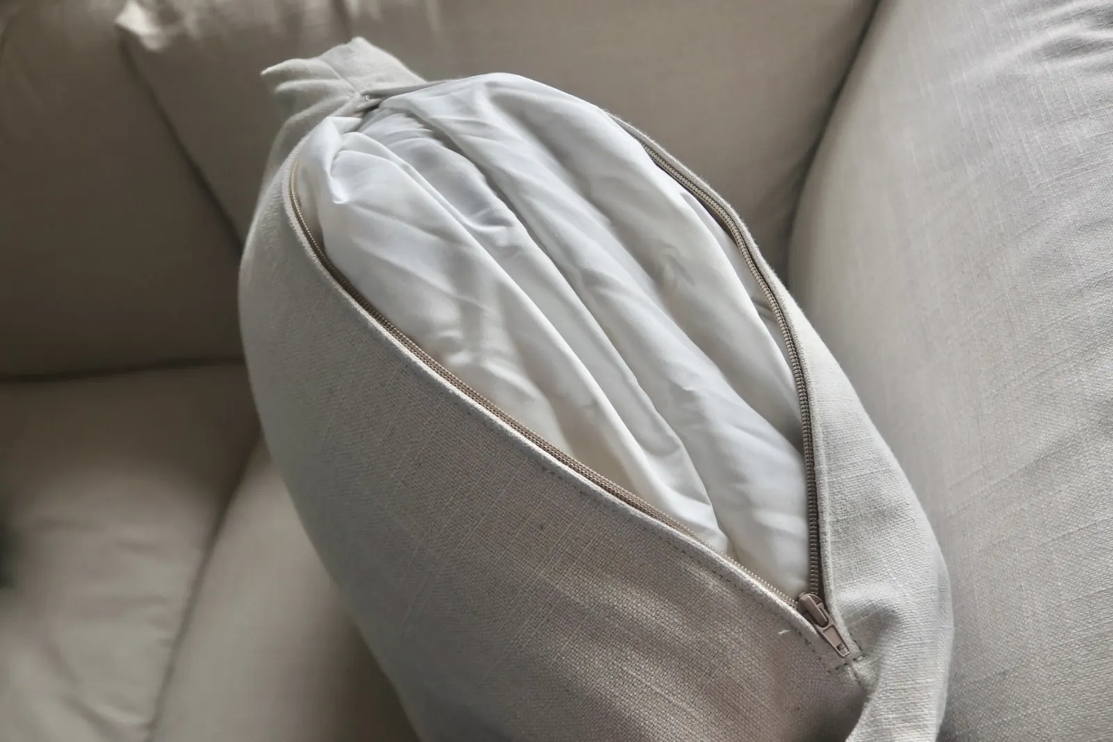 A seat cushion cover unzipped on the Sundays Get Together sofa, showing the removable cover and inner cushion